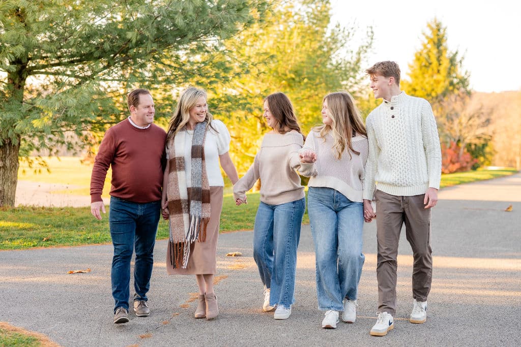 Family of five in coordinated earth-tone fall outfits walking together during an outdoor family photo session in Pittsburgh
