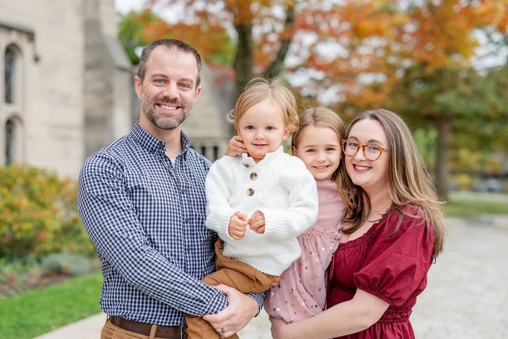 Family in coordinated rust, navy, and cream fall outfits during a Pittsburgh family photo session with autumn foliage